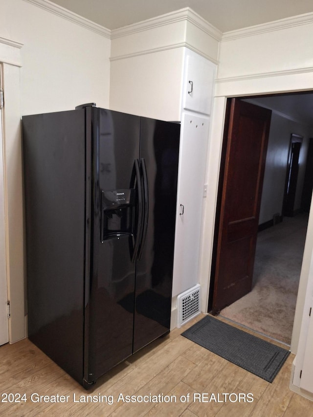 kitchen featuring black fridge, light wood-type flooring, and ornamental molding