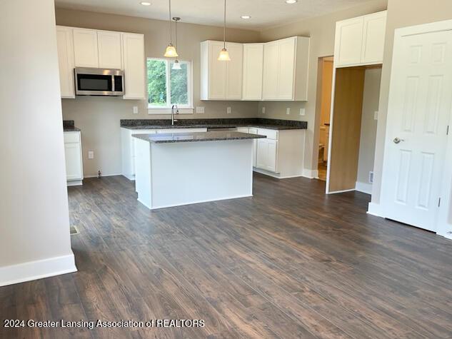 kitchen with dark hardwood / wood-style floors, a kitchen island, white cabinetry, and hanging light fixtures