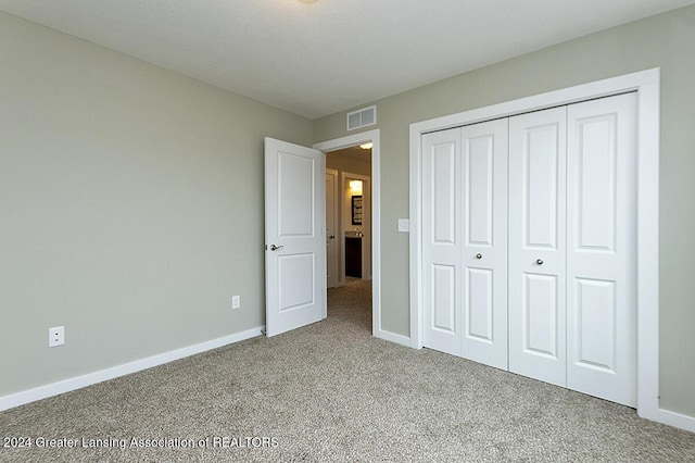 unfurnished bedroom featuring light carpet and a closet