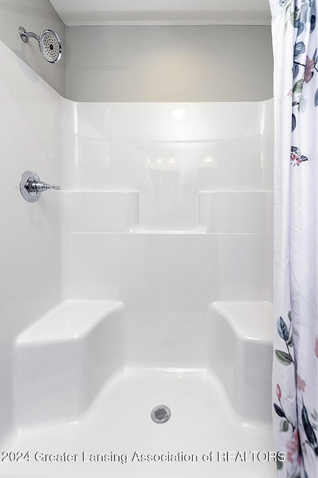 bathroom featuring a shower with shower curtain and a textured ceiling