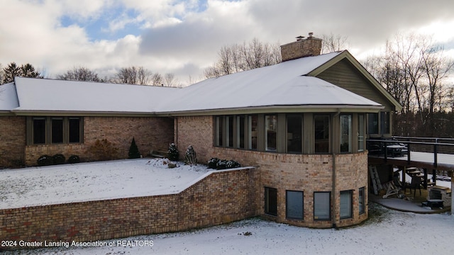 snow covered rear of property featuring a deck