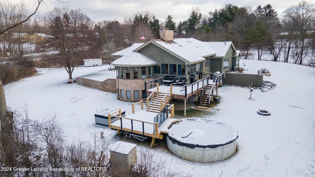 snow covered rear of property with a wooden deck