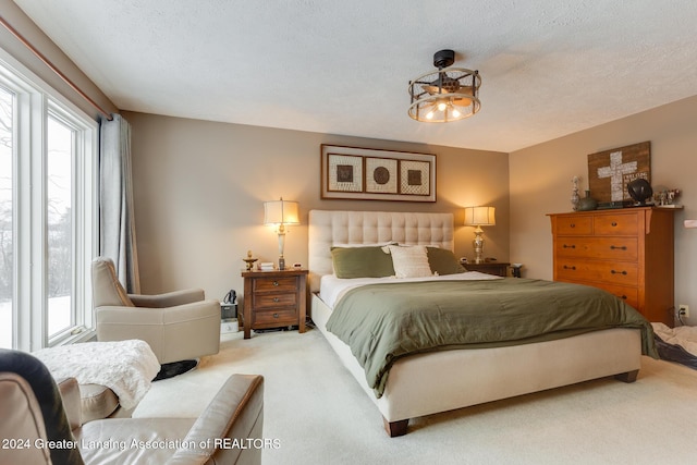 bedroom featuring a textured ceiling and light colored carpet