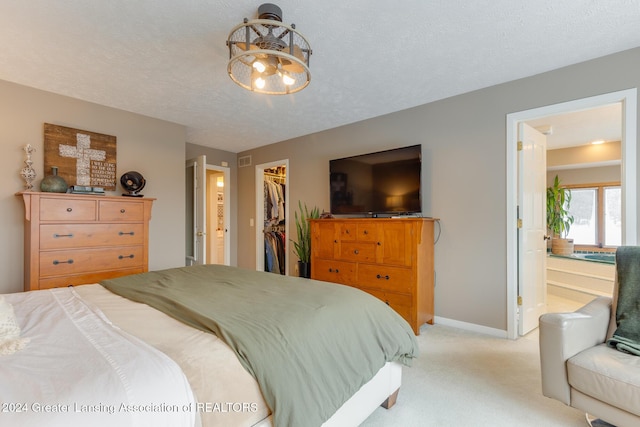 carpeted bedroom featuring ensuite bathroom, a spacious closet, a textured ceiling, and a closet