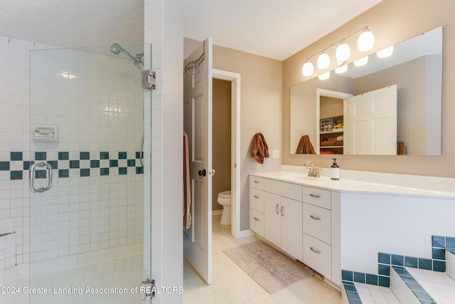 bathroom with a shower with door, vanity, and toilet