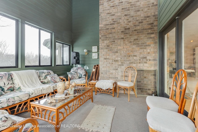 living room featuring carpet floors, brick wall, and a high ceiling