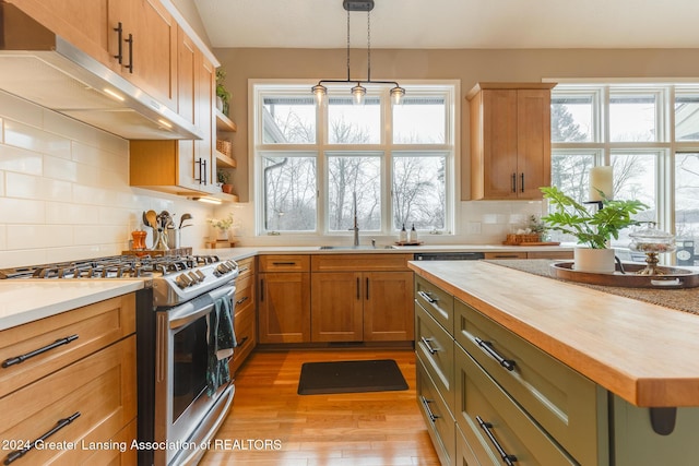 kitchen featuring wooden counters, stainless steel range with gas cooktop, hanging light fixtures, green cabinetry, and tasteful backsplash