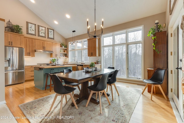 dining area featuring sink, a healthy amount of sunlight, light wood-type flooring, and an inviting chandelier