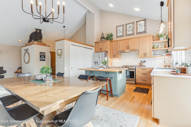 dining area featuring sink, high vaulted ceiling, a chandelier, and light wood-type flooring