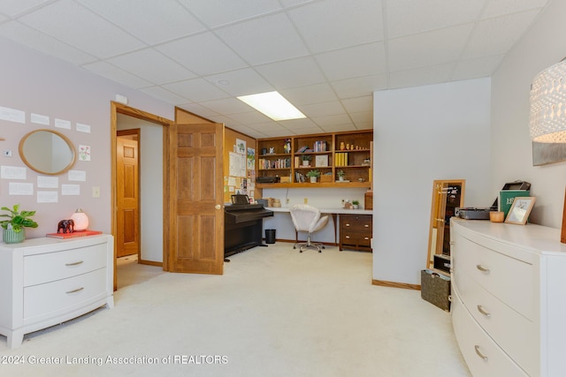 office area with a drop ceiling, built in features, light colored carpet, and built in desk