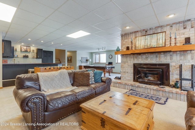 carpeted living room with a paneled ceiling and a fireplace