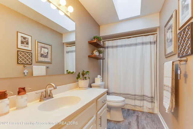 bathroom with a skylight, a shower with curtain, hardwood / wood-style floors, toilet, and vanity