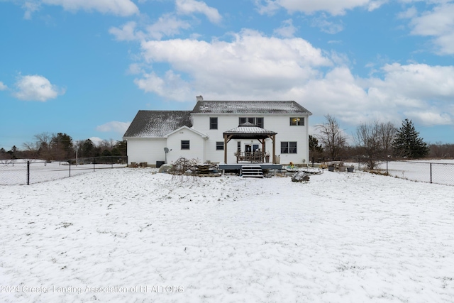 snow covered back of property with a gazebo and a wooden deck