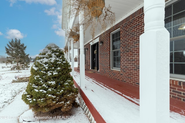 view of snowy exterior featuring covered porch