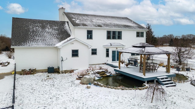 snow covered back of property with a gazebo and a deck