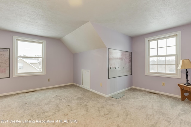 bonus room featuring light colored carpet, lofted ceiling, a textured ceiling, and a wealth of natural light