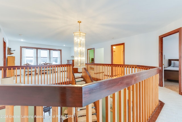 hall featuring a notable chandelier and light colored carpet