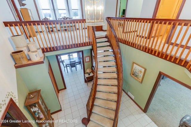 stairs with a chandelier and tile patterned floors