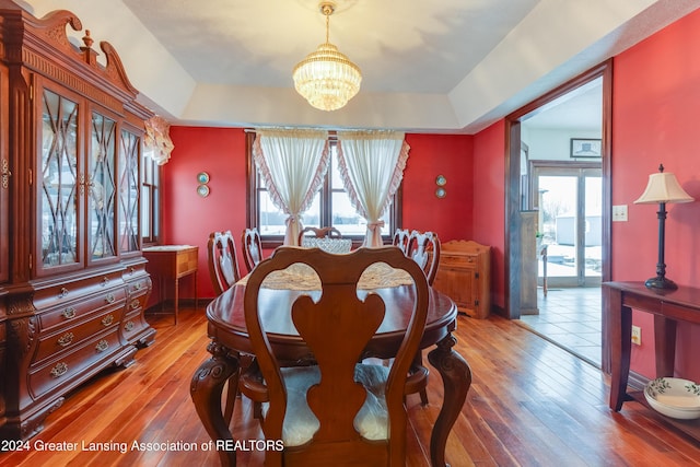 dining area with a raised ceiling, a healthy amount of sunlight, and hardwood / wood-style flooring