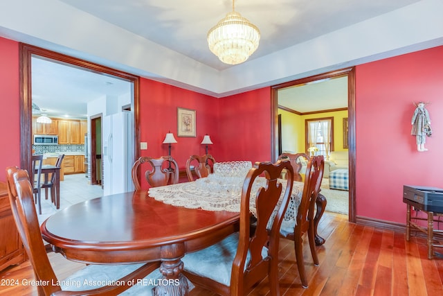 dining area with light hardwood / wood-style floors and an inviting chandelier