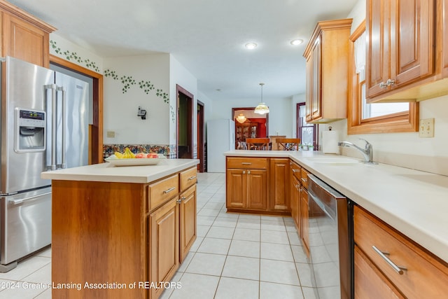 kitchen featuring sink, kitchen peninsula, decorative light fixtures, light tile patterned flooring, and appliances with stainless steel finishes