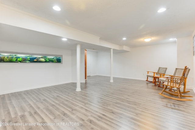 basement with light wood-type flooring and ornamental molding