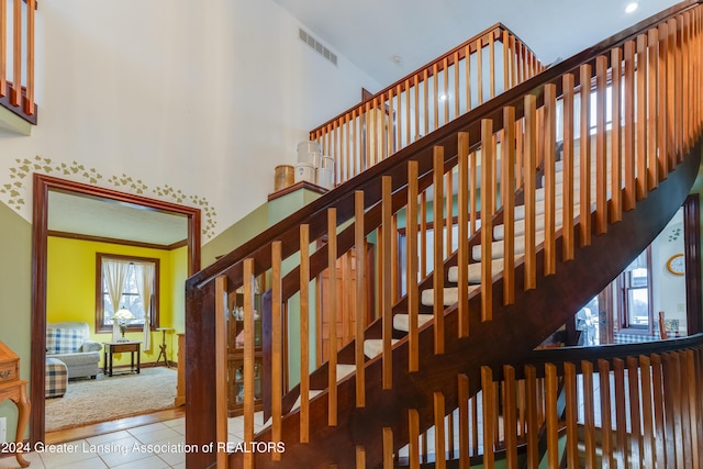 stairs with tile patterned floors and ornamental molding