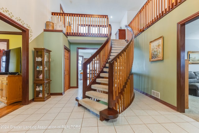 staircase featuring tile patterned flooring and a high ceiling