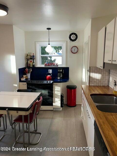 kitchen featuring electric stove, pendant lighting, dishwasher, white cabinetry, and butcher block counters