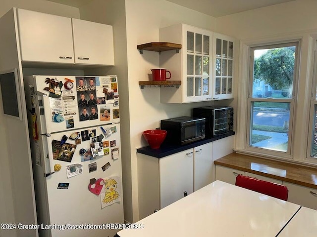 kitchen featuring white fridge and white cabinetry