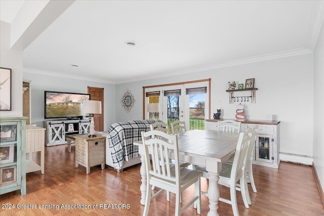 dining area featuring french doors, wood-type flooring, crown molding, and a baseboard heating unit