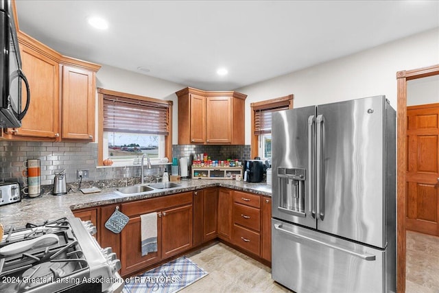 kitchen featuring stainless steel fridge with ice dispenser, backsplash, white gas stove, and sink