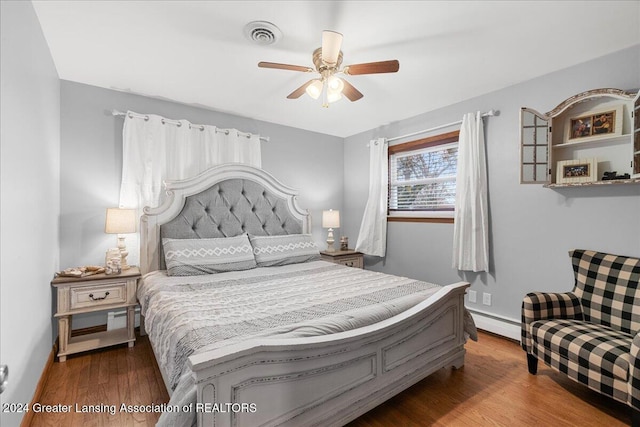 bedroom featuring hardwood / wood-style flooring, ceiling fan, and baseboard heating