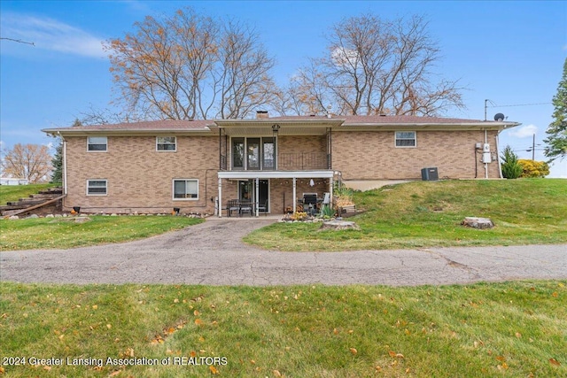 rear view of property featuring a yard and central AC unit