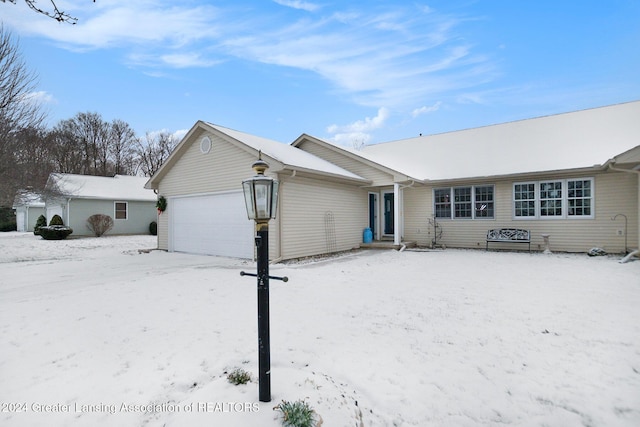 snow covered rear of property featuring a garage