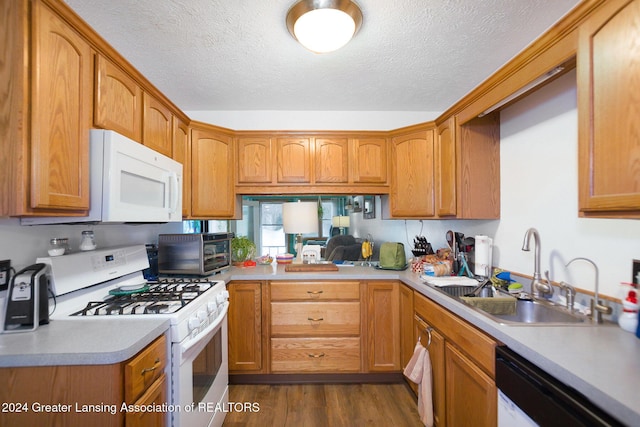 kitchen featuring wood-type flooring, white appliances, a textured ceiling, and sink