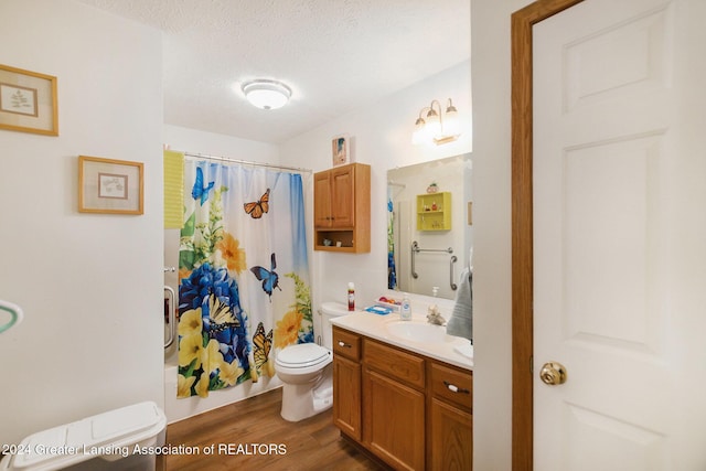 full bathroom featuring vanity, a textured ceiling, shower / bath combo with shower curtain, hardwood / wood-style floors, and toilet