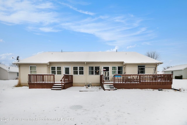 snow covered back of property featuring a wooden deck