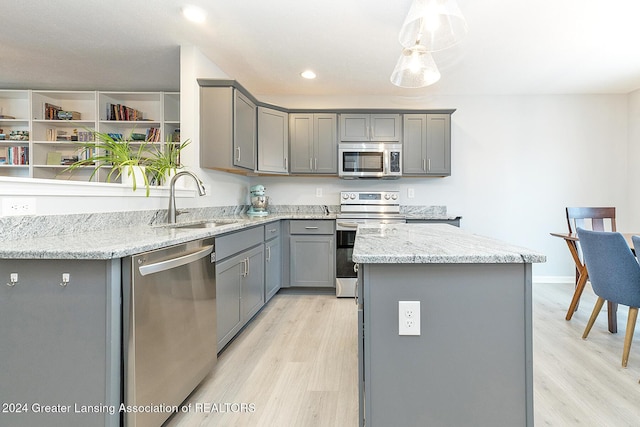 kitchen featuring a center island, stainless steel appliances, gray cabinets, and sink