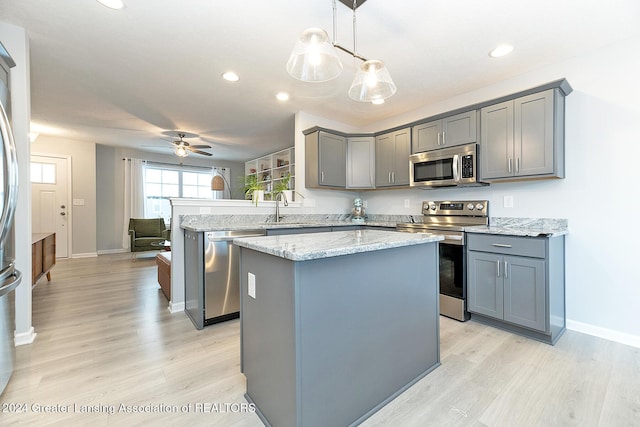 kitchen with ceiling fan, sink, hanging light fixtures, stainless steel appliances, and a kitchen island