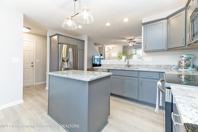 kitchen with ceiling fan, a center island, sink, stainless steel appliances, and pendant lighting