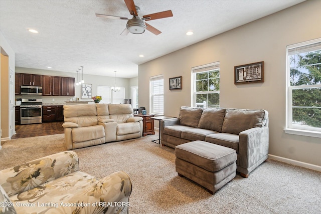 carpeted living room featuring ceiling fan with notable chandelier and a textured ceiling