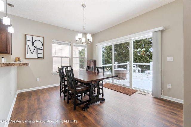 dining area with dark hardwood / wood-style flooring and an inviting chandelier