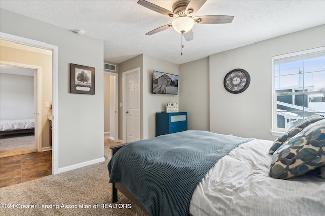 bedroom featuring dark colored carpet, a textured ceiling, and ceiling fan