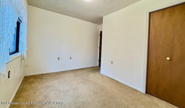 unfurnished bedroom with a textured ceiling and light colored carpet