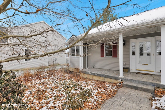 snow covered property entrance featuring a porch