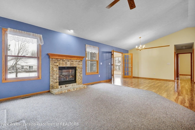 unfurnished living room with carpet, ceiling fan with notable chandelier, vaulted ceiling, and a brick fireplace