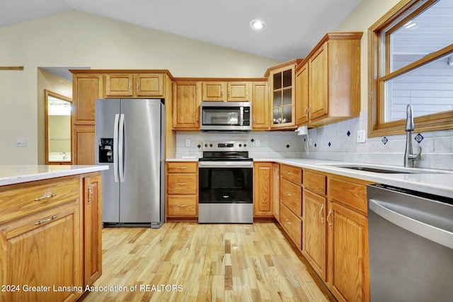 kitchen with backsplash, sink, vaulted ceiling, and appliances with stainless steel finishes