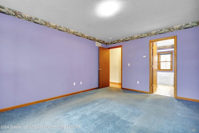 carpeted empty room with a textured ceiling