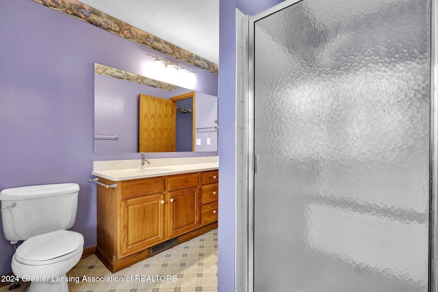 bathroom with vanity, toilet, and a shower with door